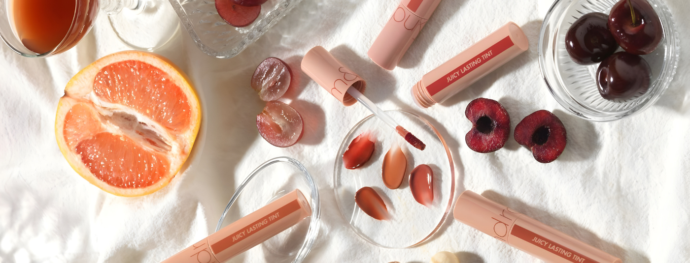 Lip glosses with cherry and grapefruit elements on a white background